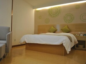 A modern hotel room with a bed, a chair, and a wall with circular patterns. - Greentree Heze Changcheng Road Tianhua Ecommerce Logistics Park Express Hotel (Heze)