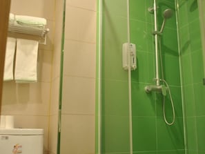 Un baño con una pared de azulejos verdes, un toallero blanco y una ducha con cabezal de ducha de mano.