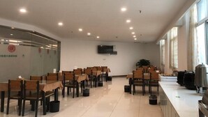 Un salón de conferencias con filas de sillas de madera, una pizarra y un televisor en la pared.