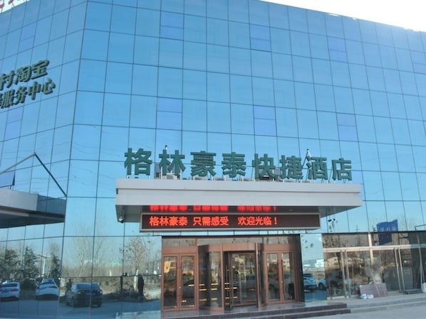A modern building with a glass facade and a sign indicating it is a hotel. - Greentree Heze Changcheng Road Tianhua Ecommerce Logistics Park Express Hotel (Heze)
