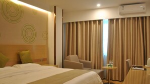 Habitación de hotel con una cama grande, una silla, una mesita con una bebida y una ventana con cortinas.