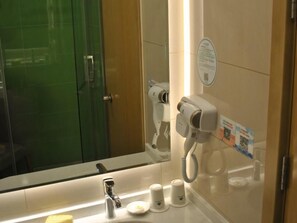 Ein Badezimmer mit Spiegel, Föhn, Waschbecken und Handtuchhalter.