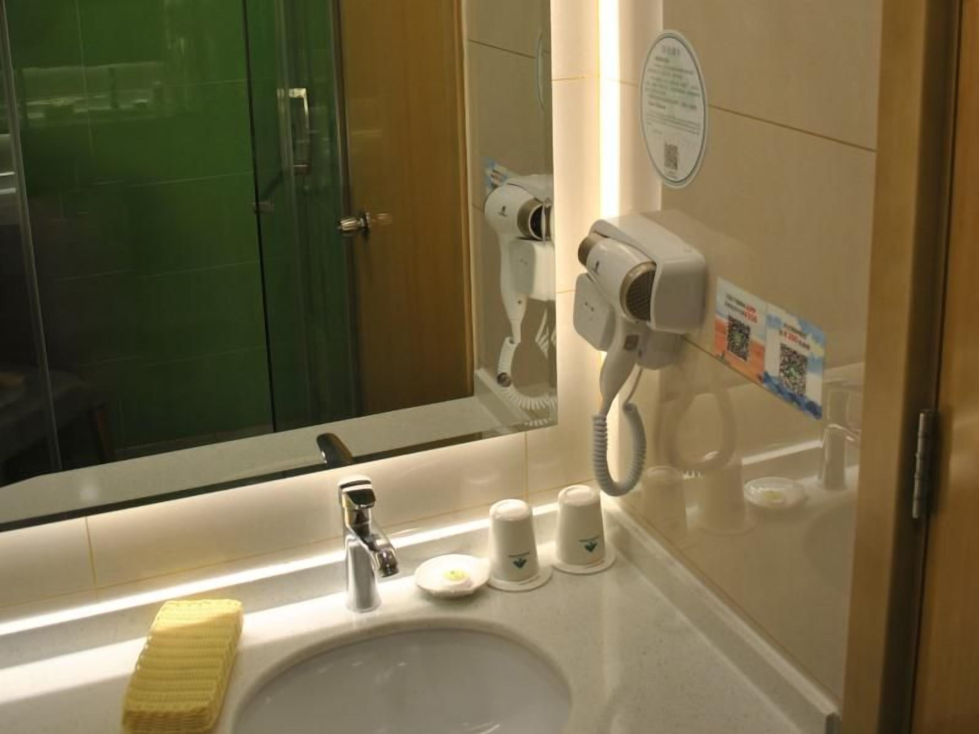 Une salle de bain équipée d’un lavabo, d’un miroir, d’un sèche-cheveux et d’une douche en verre.