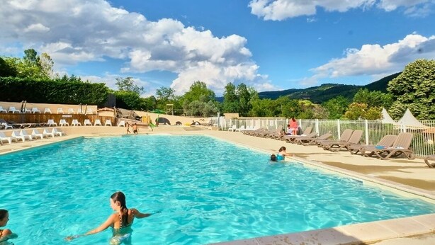 Una piscina con sillones de descanso y vistas del paisaje circundante.