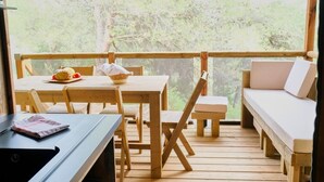 Una terraza de madera con una mesa, sillas y un banco.