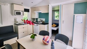 Una kitchenette compacta con microondas, pileta y hornalla, un comedor con mesa y sillas, y una pequeña sala de estar con sofá.
