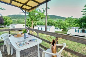 A covered outdoor seating area with a table, chairs, and a decorative vase. - Ludo Camping Parc (Lussas)