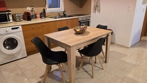 Ett kompakt kök med ett träbord, svarta stolar, en tvättmaskin och ett handfat.