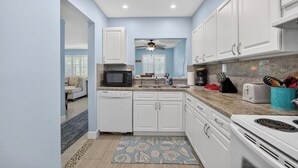 A modern kitchen with white cabinets, a microwave, a sink, and a stove. - Eden's Reef : 3bed/3bath (Lauderdale by the Sea)