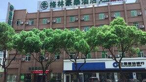 Ein Hotel mit Schildern, einer Filiale der China Construction Bank und Bäumen davor.