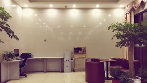 Eine moderne Lobby mit einer Rezeption, einer Sitzecke und Topfpflanzen.