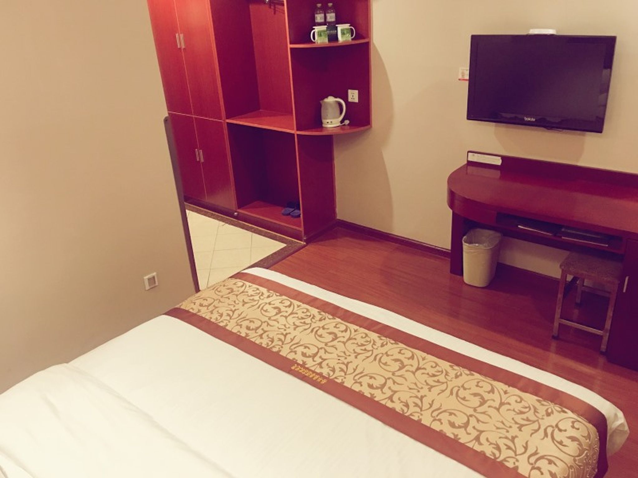 A hotel room with a bed, a TV, a desk, and a wardrobe.