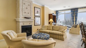 Una sala de estar con chimenea, un conjunto de sofás y un ventanal con cortinas.