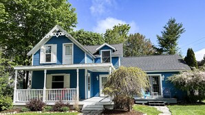 Une maison bleue à deux étages, dotée d’un porche à l’avant, d’un petit jardin et d’un chemin de pierre menant à l’entrée.