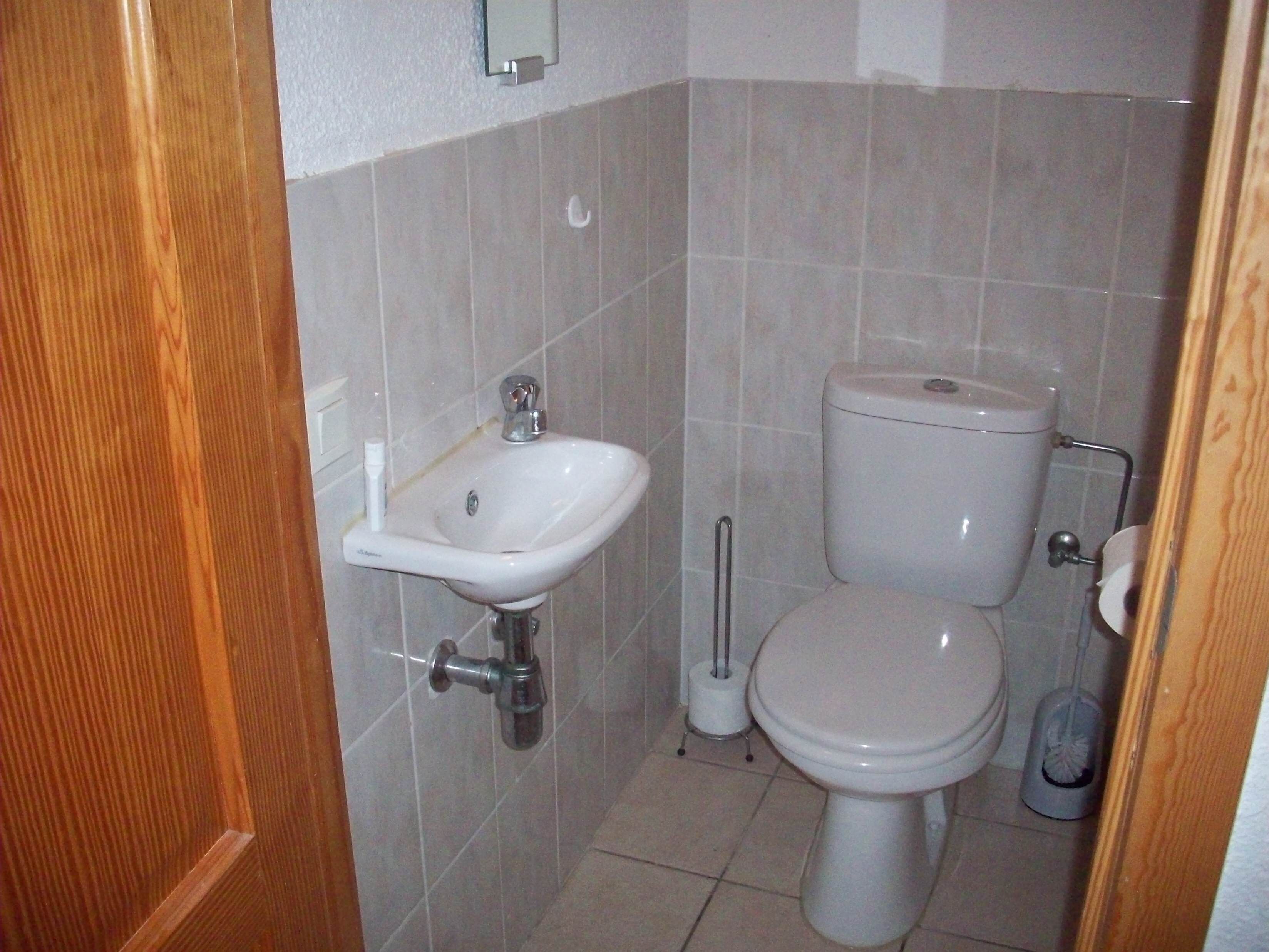 Une petite salle de bain avec un lavabo blanc, des toilettes et un bidet.