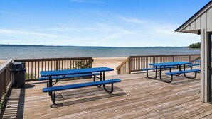 A wooden deck with picnic tables overlooking a body of water.