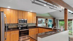 A kitchen with wooden cabinets, stainless steel appliances, and a large island with a sink.