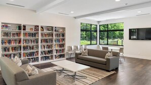Ein modernes Wohnzimmer mit einer großen Bücherwand, einem Sofa, einem Couchtisch und einem an der Wand montierten Fernseher.