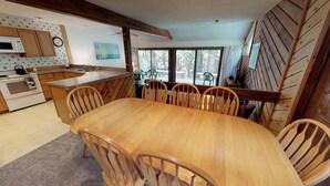 A wooden dining table with six chairs, a kitchen with wooden cabinets, a microwave, and a stove. - Harbor Cove! 5 Bedroom! #82 Ski, Golf, Shop! (Harbor Springs)