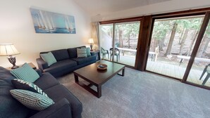A living room with a sofa, a coffee table, and a painting of sailboats. - Harbor Cove! 5 Bedroom! #82 Ski, Golf, Shop! (Harbor Springs)