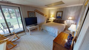 Un dormitorio con cama, televisión, silla y lámpara.