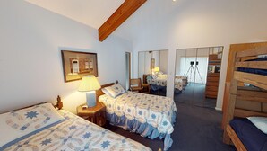 Une chambre avec deux lits, un miroir, une lampe et une poutre en bois au plafond.