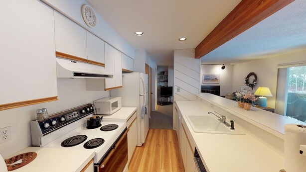 Une cuisine moderne avec des meubles blancs, une cuisinière, un four à micro-ondes et un évier.