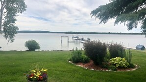 Blick auf einen See mit Steg, Rasenfläche und Blumenbeet.