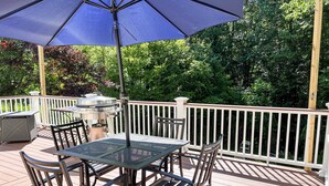 A deck with a table and chairs, a grill, and a large umbrella. - COMFORTABLE & SPACIOUS Home in Harbor Springs - Minutes from the Ski Hills!! (Harbor Springs)