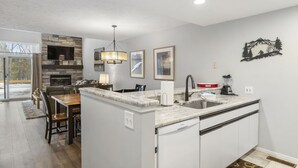 A modern kitchen with a stone backsplash, a built-in island, and a large window. - Trout Creek #122 SHUTTLE TO NUBS! POOLS &Fitness! (Harbor Springs)