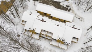 A two-story building with a flat roof and multiple windows, surrounded by snow-covered trees. - Trout Creek #122 SHUTTLE TO NUBS! POOLS &Fitness! (Harbor Springs)