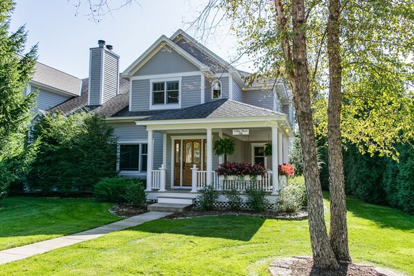 A two-story house with a front porch, a chimney, and a well-maintained lawn.