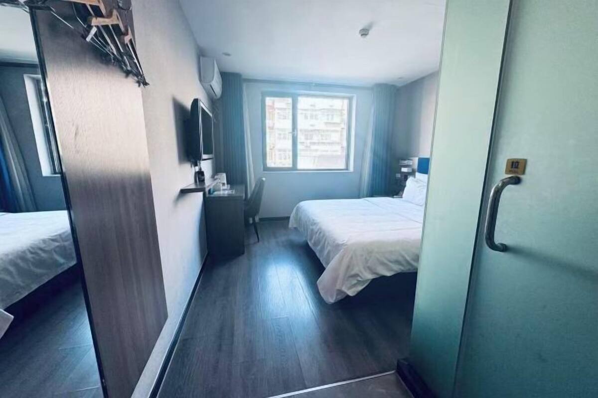 Une chambre d’hôtel avec un lit, une télévision, une fenêtre et une porte.
