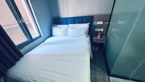 Une chambre d’hôtel avec un lit, une table de chevet, une fenêtre et une porte.