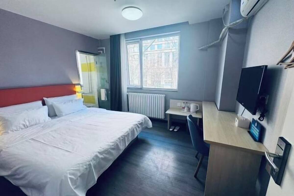 Une chambre d’hôtel avec un lit, un bureau, une télévision et une fenêtre.