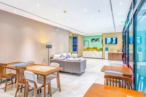 Un hall de hotel con mostrador de recepción, zona de estar y comedor.