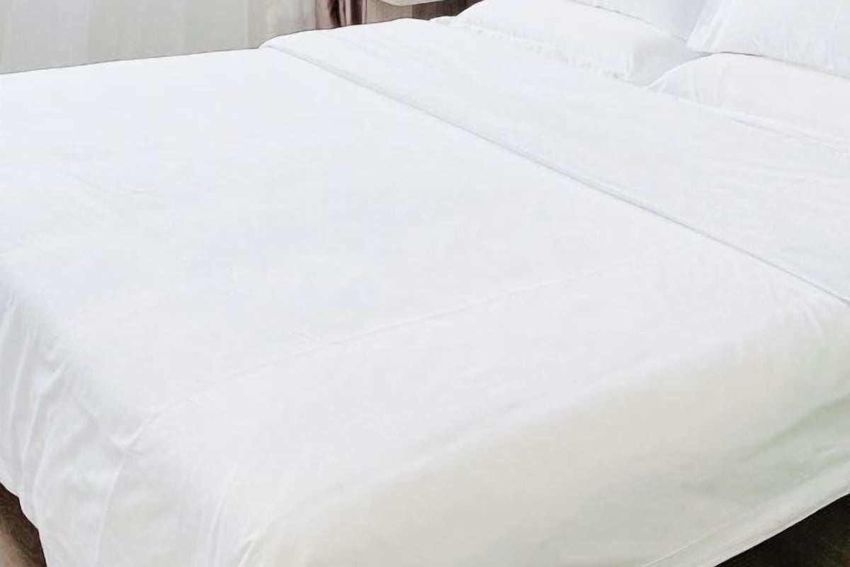 A neatly made bed with a white bedspread and pillows.