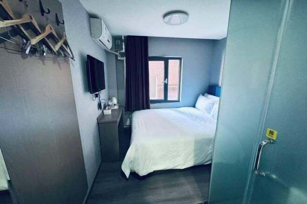 Une chambre d’hôtel avec un lit, une télévision, une fenêtre et une porte.