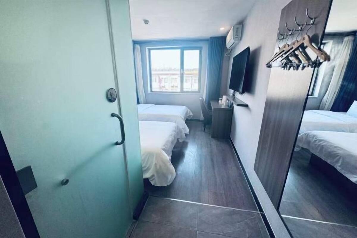 Une chambre d’hôtel avec deux lits, un bureau, un miroir et une fenêtre donnant sur un paysage agréable.