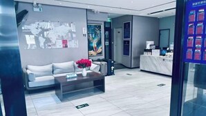 Un hall d’hôtel moderne avec un comptoir d’accueil, un canapé, une table basse agrémentée de fleurs et une carte du monde accrochée au mur.