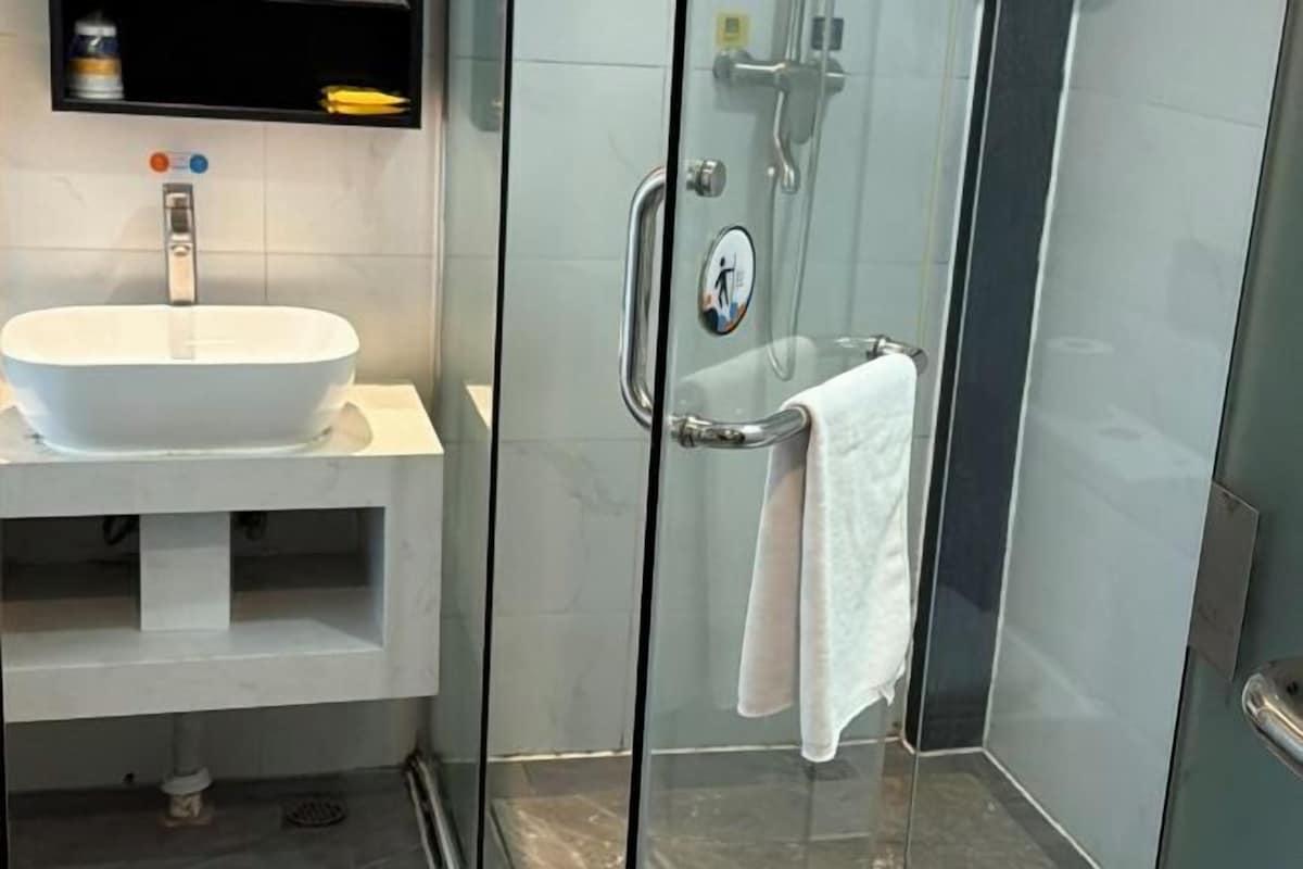 A bathroom with a white sink, glass shower enclosure, and a towel rack.