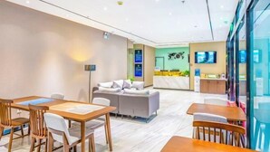 Un hall d’hôtel moderne avec un comptoir d’accueil, un espace salon et une grande fenêtre.