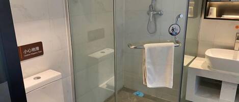 A modern bathroom with a glass shower enclosure, a white sink, and a toilet.