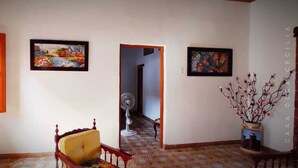 A room with a wooden chair, a fan, and two framed pictures on the wall. - Casa Olga Cecilia (Honda)