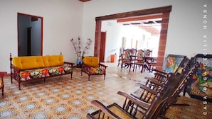 A room with a patterned floor, a sofa, chairs, and a dining area with chairs and a table. - Casa Olga Cecilia (Honda)