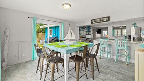 Een eetruimte met een tafel gedekt voor vier personen, een keuken op de achtergrond, en een bordje met de tekst 'FISH STORIES TOLD HERE'.