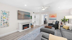 Una sala de estar moderna con chimenea, televisión y ventilador de techo.