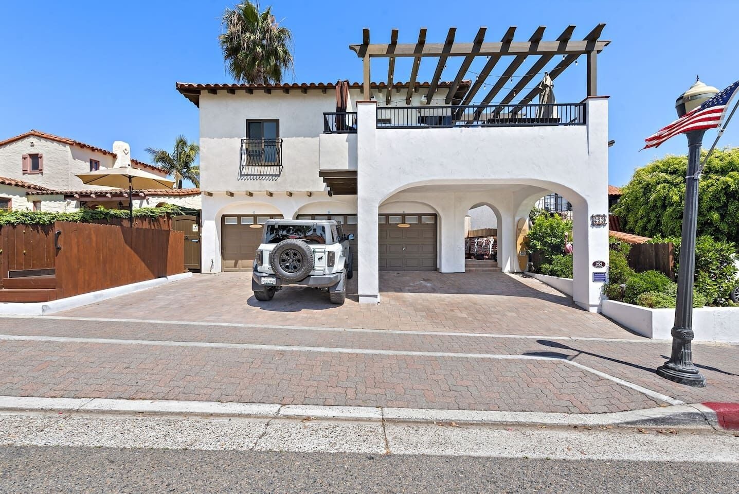 Uma casa de dois andares com garagem, entrada por meio de rampa e um pergolado.