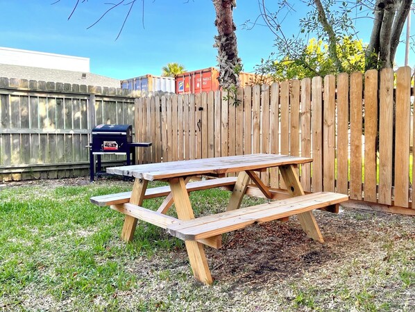 A wooden picnic table with benches in a backyard.