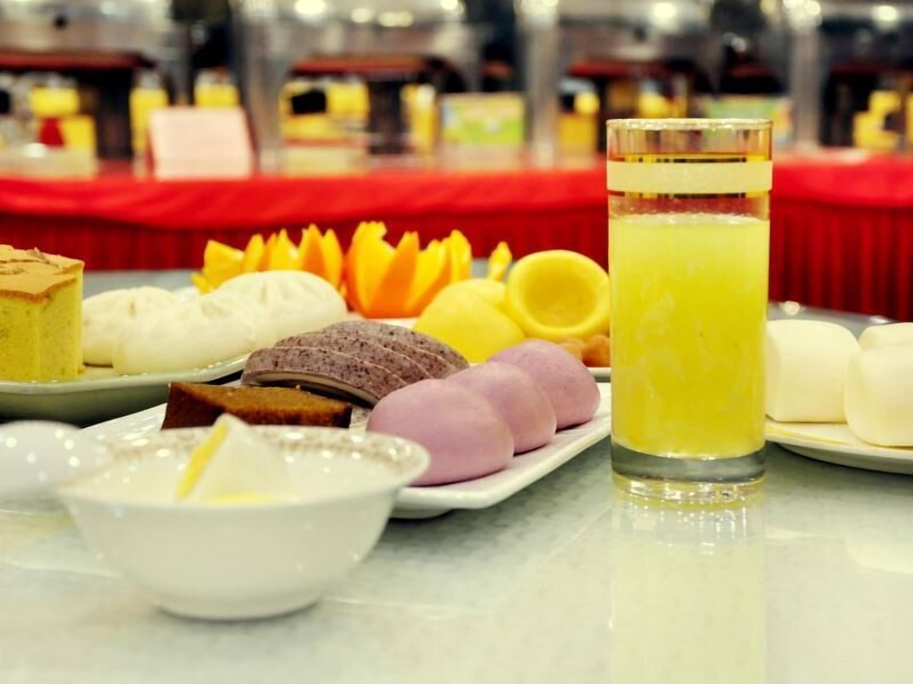 En morgenmadsbuffet med forskellige bagværk, et glas appelsinjuice og en skål suppe.